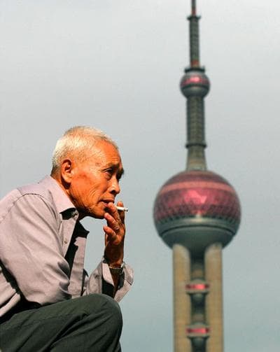 An elderly man smokes near Shanghai's Oriental TV Tower on Sept. 10, 2004. (AP Photo)