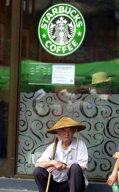 A Chinese tourist takes a break in front of a Starbucks coffee shop at Yu Garden in Shanghai, China on July 15, 2002. (AP Photo/Eugene Hoshiko)