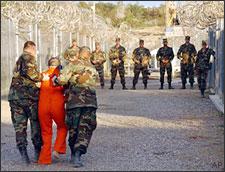 Army Military Police escort a detainee to his cell in Camp X-Ray at Naval Base Guantanamo Bay, Cuba, on Jan. 11, 2002. (AP)