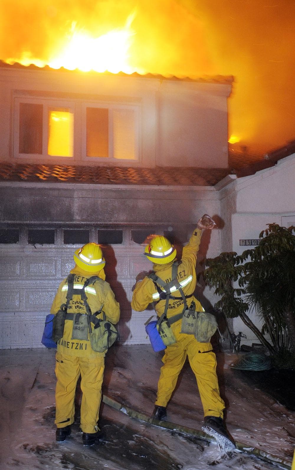 (AP) Firefighters throw a rock through a window to spray water inside a home in Los Angeles in 2008. 