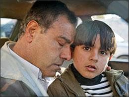 Dr. Izzeldin Abuelaish, a Palestinian doctor and peace activist who trained in Israel and became a regular fixture on Israeli television, rests his head on his son Abdullah, 6, in a car before traveling to Israel with his children, near his house in Jebaliya, in the northern Gaza strip, Wednesday, Jan. 21, 2009. Three of his daughters and a niece were killed by an Israeli shell which struck his house, and he returned to Gaza Wednesday to collect his remaining children. (AP)