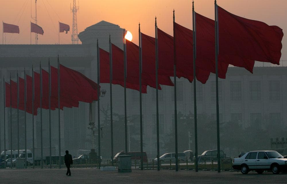 A lone man walks alongside red flags after the clearing Tiananmen square for security reasons ahead of  the opening session of the National People's Congress in  Beijing's Great Hall of the People Sunday, March 5, 2006. (AP