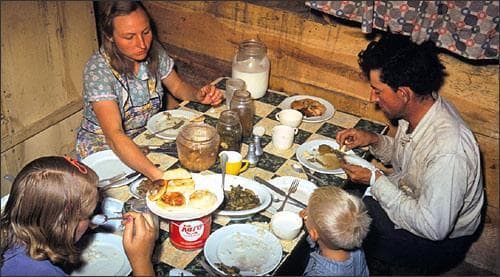 The Faro Caudill family eating dinner in their dugout, Pie Town, New Mexico. October 1940. Photo by Russell Lee.