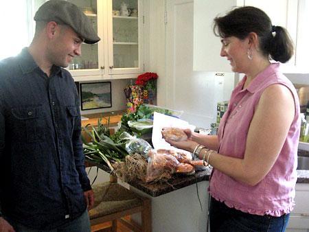 Marketing expert Valerie Gates receives fresh, prepared meals from Jake Ferreira of Beetlebung Farm LLC in her Wellesley, Mass., kitchen. Gates devised a barter system in which she gives marketing advice to New England farms in exchange for food. (Andrea Shea/WBUR)
