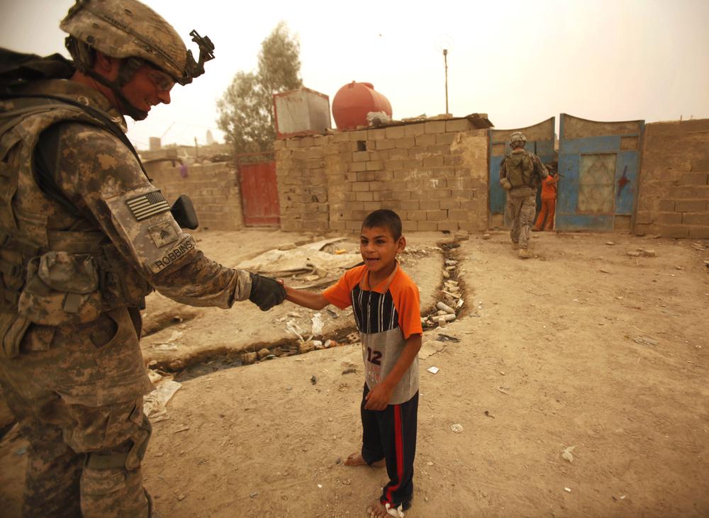 A U.S. Army soldier greets an Iraqi child during routine patrol in the Shiite enclave of Sadr City in Baghdad, Iraq, Sunday, June 28, 2009. U.S. troops will be out of Iraqi cities by Tuesday June 30 in the first step toward winding down the American war effort by the end of 2011. (AP)