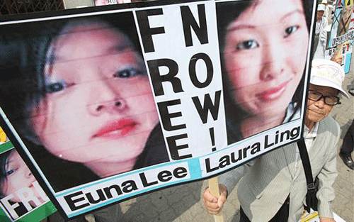 A South Korean protester displays portraits of American journalists detained in North Korea. Laura Ling and Euna Lee have been convicted of entering North Korea illegally and engaging in &quot;hostile acts.&quot; Laura Ling and Euna Lee, reporters for former U.S. Vice President Al Gore 's California-based Current TV media venture, were arrested March 17 near the North Korean border while on a reporting trip to China. (AP)