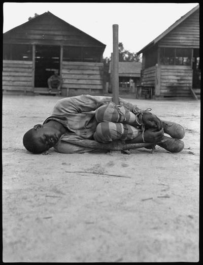 An unnamed prisoner tied around a pickax for punishment in a Georgia labor camp. Photograph by John L. Spivak, during research for his 1932 book, &quot;Georgia Nigger.&quot;
