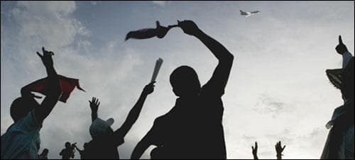 Supporters of ousted Honduras' President Manuel Zelaya cheer as his airplane flies overhead at the international airport in Tegucigalpa, Sunday, July 5, 2009. (AP)