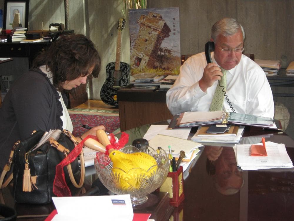 Boston Mayor Thomas Menino conducts a phone interview with a Boston Globe reporter in his City Hall office overlooking Faneuil Hall while press secretary Dot Joyce writes his talking points. (Fred Thys/WBUR)