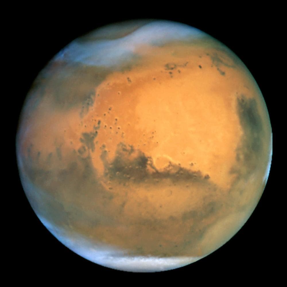 In an image that scientists call the sharpest image ever made from Earth, the planet Mars is seen as a dynamic planet covered by frosty white water ice clouds and swirling orange dust storms above a vivid rusty landscape, in this view made by the Earth-orbiting Hubble Space Telescope on June 26, 2001. Details as small as 10 miles (16 km) across can be seen. The colors have been balanced to give a realistic view of Mars' hues as they might appear through a telescope. Scientists are especially interestedin the large amount of seasonal dust storm activity seen. One large storm system is churning high above the northern polar cap, top left center, with another large dust storm spilling out of the giant Hellas impact basin in Mars' Southern Hemisphere at lower right. (AP Photo/NASA and Hubble Heritage Team)