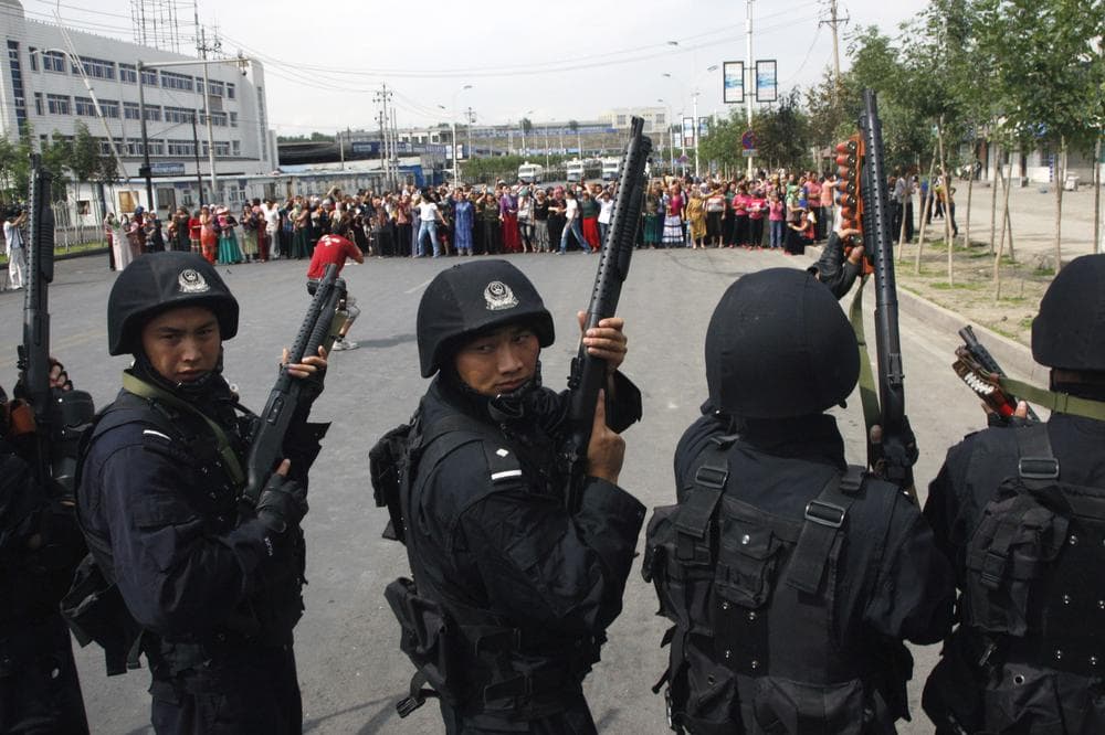 Heavily-armed special police officers face off a crowd of Uighur residents after they staged a protest in Urumqi, capital of northwest China's Xinjiang Uygur Autonomous Region, Tuesday, July 7 , 2009. Ethnic Uighurs scuffled with armed police Tuesday in a fresh protest in the western region of Xinjiang, where at least 156 people have been killed and more than 1,400 people arrested in western China's worst ethnic violence in decades. (AP Photo/Ng Han Guan)