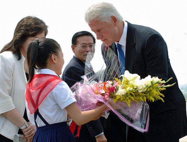Former U.S. President Bill Clinton, right, receives a bouquet of flowers upon his arrival at an airport in Pyongyang on a surprise mission to bring home two jailed American journalists. (AP Photo/Korean Central News Agency)