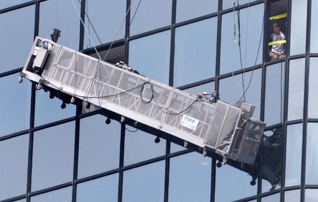 An unidentified man peers out a broken window after firefighters safely rescued two window washers after their platform malfunctioned 37 floors above street level in Boston on Wednesday. (AP)