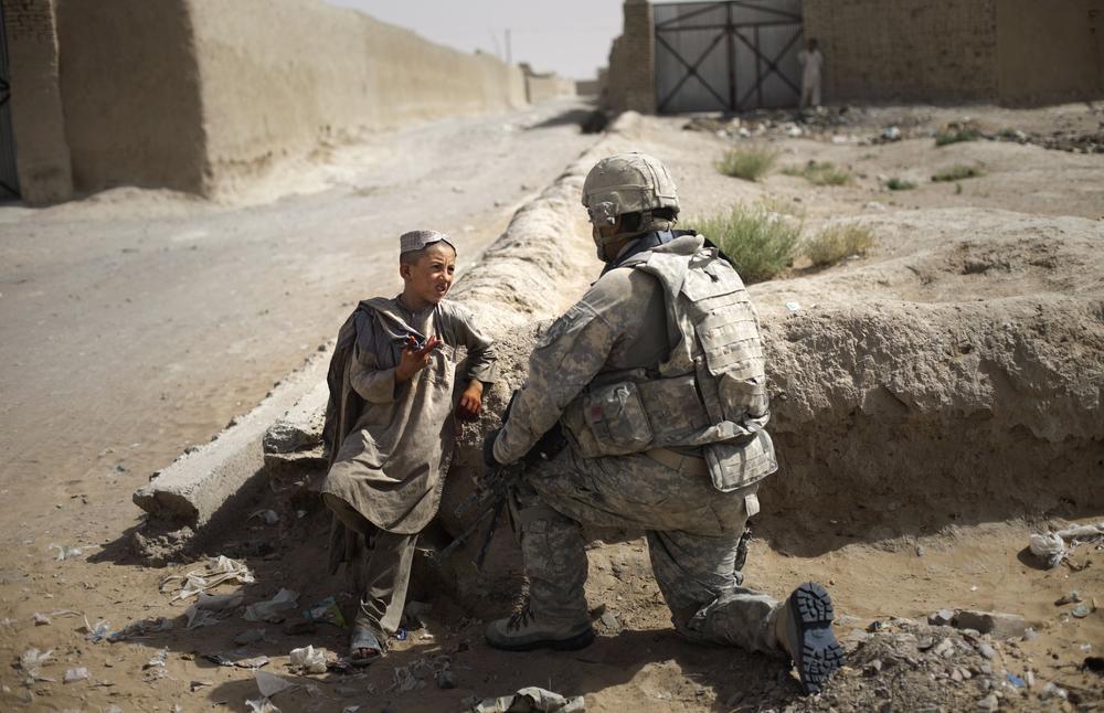 Afghan youth Asad Ullah, 10, talks with Private First Class U.S. soldier, Ryan Hayes, from the 2-1 Infantry, 5th. Striker Brigades, as he guards a position in a village in the outskirts of Spin Boldak, about 100 kilometers (63 miles) southeast of Kandahar, Afghanistan, Thursday,  Aug. 6, 2009. Thousands of U.S. troops are deploying in southern Afghanistan as part of an effort to prevent the Taliban from disrupting the country's Aug. 20 presidential ballot.  (AP)