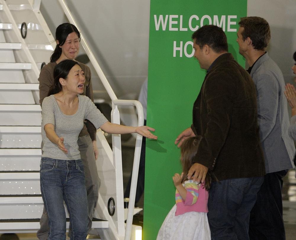 Euna Lee, left, and Laura Ling, two American journalists who were arrested in March after allegedly crossing into North Korea from China, are greeted by Michael Saldate, the husband of Euna Lee, second from right, Ian Clayton, the husband of Laura Ling, right, and Lee's daughter, Hana, after the two arrive at Bob Hope Airport in Burbank, Calif., Wednesday, Aug. 5, 2009. (AP)