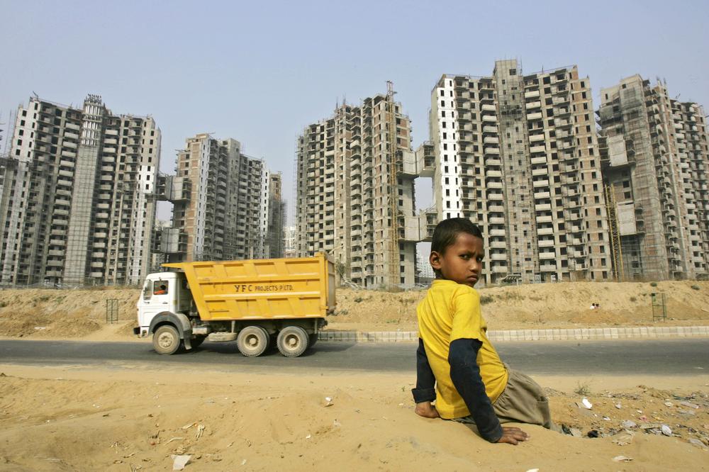 A boy sits with the backdrop of a residential complex in a partial state of construction, in Gurgaon, India, Wednesday, Nov. 19, 2008. India and China's ability to resist the global economic slowdown will greatly influence whether the crisis drags the world into a depression, a top Pacific Rim trade community economist said Tuesday. The International Monetary Fund has said emerging economies, which include China and India, will account for the world's entire projected 2.2 percent overall growth next year, adding that rich nations' economies will together grow by just 0.1 percent this year while the developing world will grow by 5 percent. (AP)