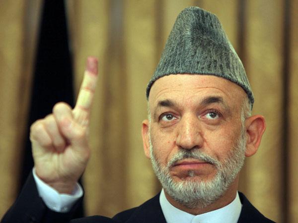 Incumbent President Hamid Karzai holds up his purple finger after casting his ballot in Kabul on Thursday. (AP)