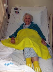 Fairview Hospital patient Jean Gutowski, 88, wears yellow socks and a yellow blanket, which indicate that she’s at high risk of falling. (Sacha Pfeiffer/WBUR)