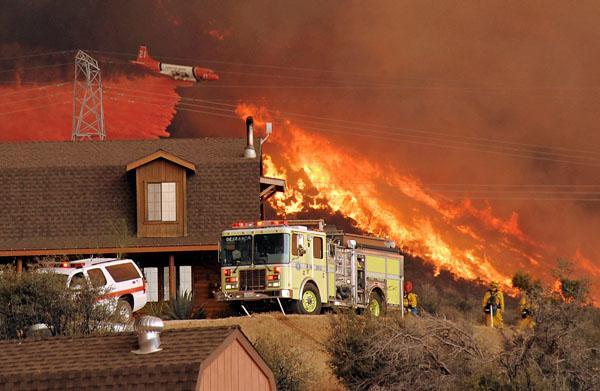 A United States Forest Service air tanker drops fire retardant next to a line of fire as the Station fire burns in the hills above a home in Acton, Calif. on Sunday. (AP)