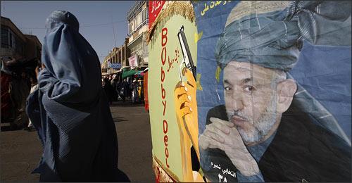 A burqa clad woman walks past a poster of Afghan President Hamid Karzai pasted on the back of a vehicle in Herat, Afghanistan, Tuesday, Aug. 18, 2009. Afghans will head to the polls on Aug. 20 to elect the new president. (AP)