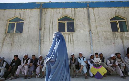 An Afghan woman voter walks past male voters lining up to cast their ballots, as she heads towards the women's side of a mosque made into a polling station in Kabul on Thursday Aug. 20, 2009. (AP) 