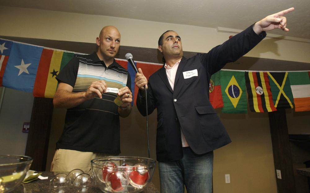 ONE Lowell World Cup soccer organizer Steve Apostolov, right, points toward the New England players as New England Revolution goalie Mike Reis holds up their country name card after their team was selected during the seeding draw in Lowell on July 16. (AP Photo/Charles Krupa)