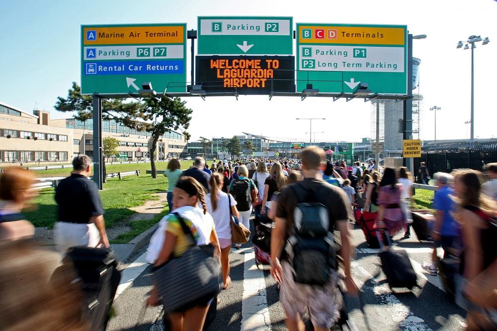 Passengers walk toward the main terminal at New York's LaGuardia Airport as it reopens after being evacuated Saturday. The airport was evacuated after a man entered the building with a fake bomb in a bag, police said. The device in the man's bag was a few batteries and wires, but it was not dangerous, police said. (AP Photo/David Goldman)