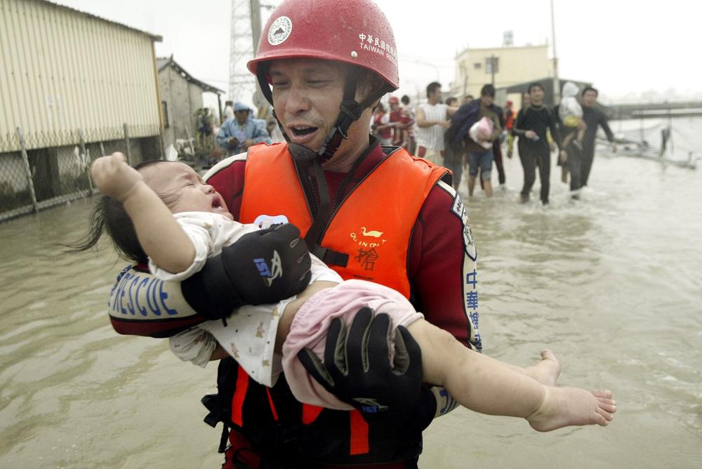 A rescuer helps a crying baby out of floodwater area after Typhoon Morakot hit Pintung county, southern Taiwan, Sunday. The storm dumped more than 80 inches of rain on some southern counties on Friday and Saturday, the worst flooding to hit the area in half a century, the Central Weather Bureau reported. (AP)