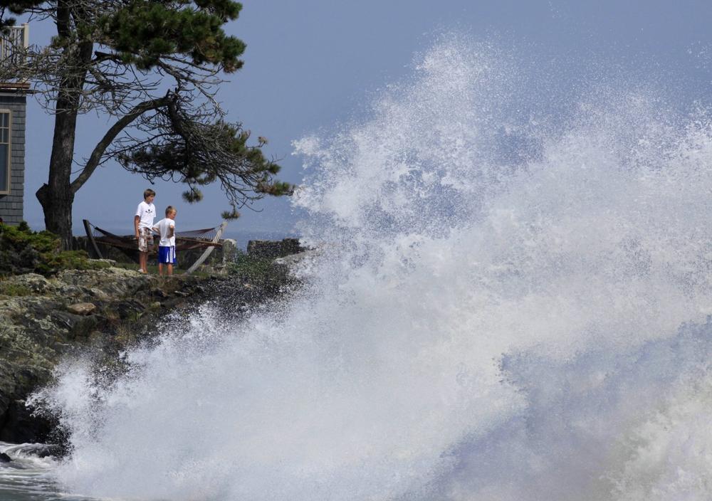 Two boys watch as heavy surf generated by Hurricane Bill pounds the shore, Sunday, in Cape Elizabeth, Maine. Officials say a large wave in Maine's Acadia National Park swept five people into the sea and three are still missing. (AP)