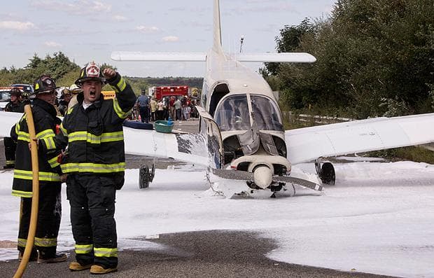 Firefighters signal other rescue personnel while applying fire retardant foam around a single engine aircraft on Interstate 495, in Mansfield, Mass., Tuesday, Sept. 1, 2009. (Steven Senne/AP Photo)