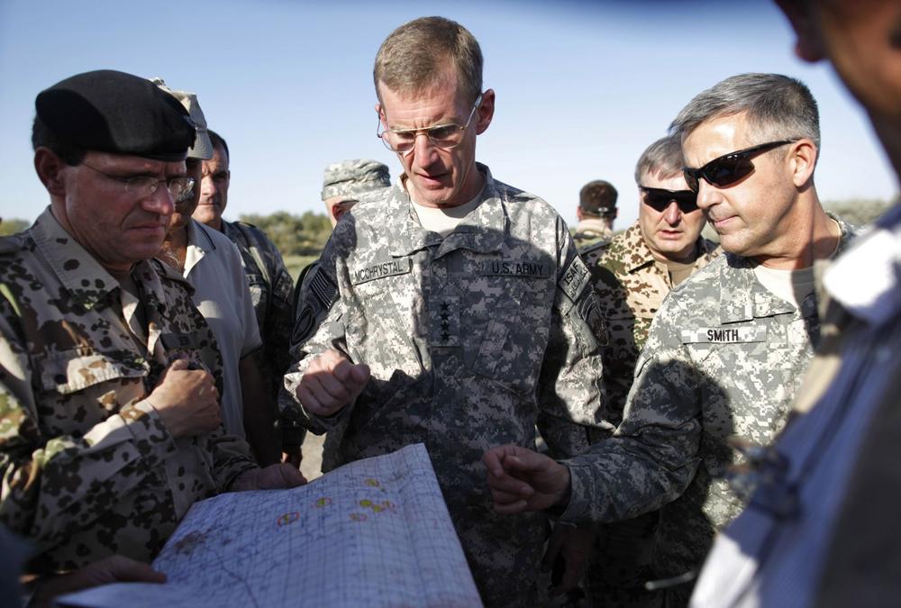 U.S. Gen. Stanley McChrystal, center, commander of U.S. and Nato forces in Afghanistan, German colonel Georg Klein, left, commander of the German base in Kunduz, and U.S. Rear Admiral Gregory J. Smith, right, NATO's director of communications in Kabul, are surrounded by Afghan and German soldiers as they visit the site where villagers reportedly died when American jets bombed fuel tankers hijacked by the Taliban, outside Kunduz, Afghanistan, Saturday. The top U.S. and NATO commander in Afghanistan visited the site as the alliance began an investigation  into the airstrike that killed up to 70 people. (Anja Niedringhaus/AP)