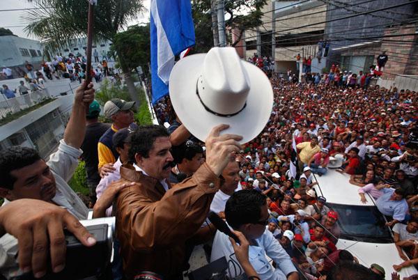 Honduras&#039; ousted President Manuel Zelaya waves to supporters from inside Brazil&#039;s embassy in Tegucigalpa on Monday. (AP)