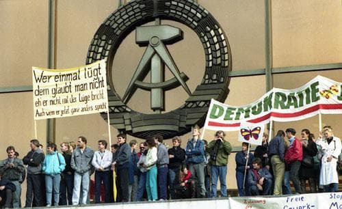 Calling for democratic reforms, some of the one million demonstrators in East Berlin on November 4, 1989, hold a sign reading &quot;Who lies once cannot be trusted&quot; at the Palace of the Republic. The building housing the Communist Parliament is decorated with the national emblem, the hammer and pair of compasses. (AP)