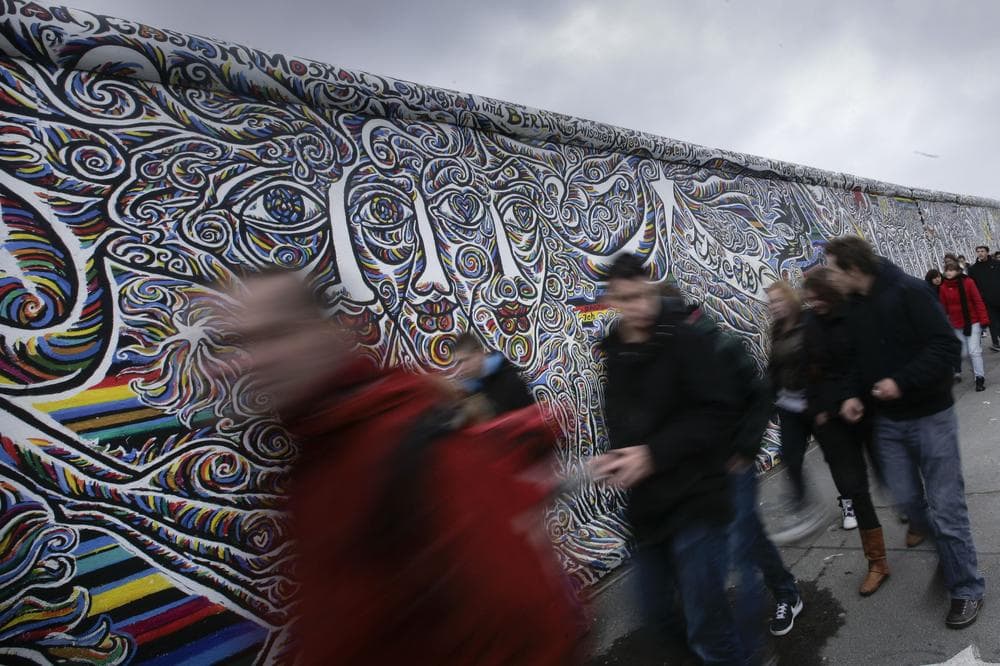 Tourists pass a painting on a segment of East Side Gallery in Berlin, Germany, Wednesday, Oct. 21, 2009. The restoration of the 105 wall paintings of the former Berlin Wall is scheduled to be finished for the 20th anniversary of the opening of the Berlin Wall in November 2009. The same 118 artists from 21 countries who created the paintings in 1990 will repaint their pictures in the world's longest open-air art gallery after replacement of the concrete surface of the Wall. (AP)