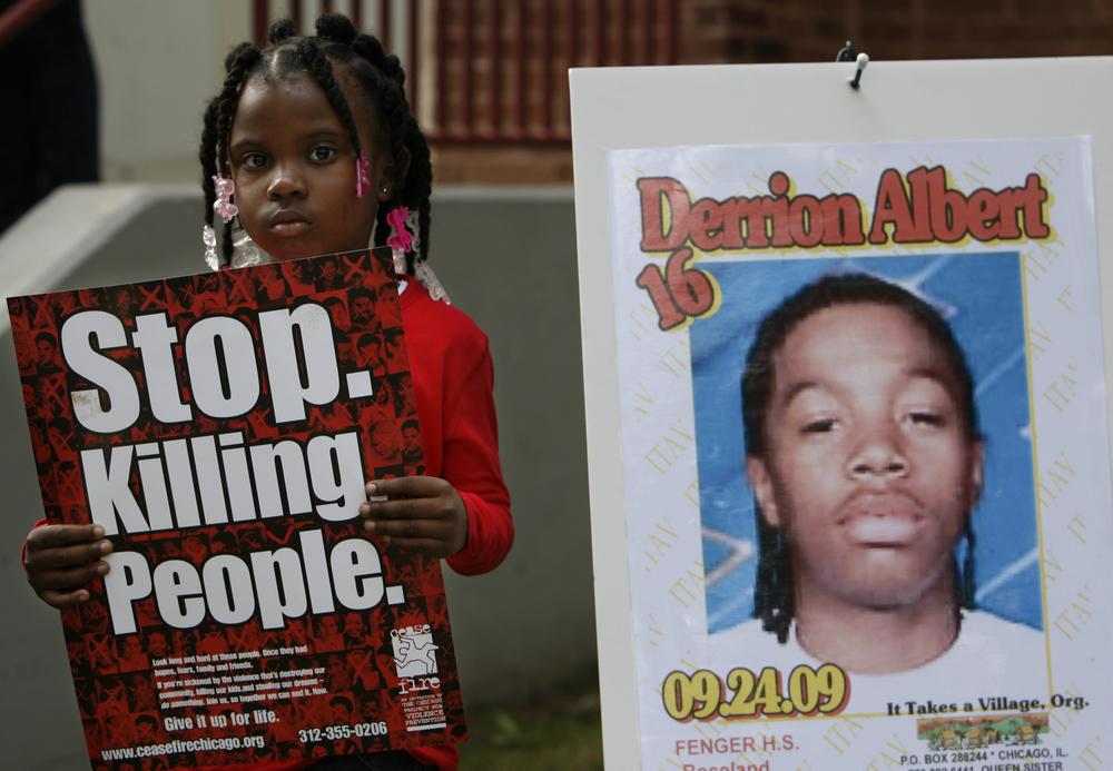 Nadashia Thomas, 6, a cousin of Derrion Albert, holds a sign beside a poster of  Derrion Albert at Fenger High School  in Chicago, Sept. 28, 2009. A vigil for Derrion Albert was planned outside of  Fenger High School. (AP)