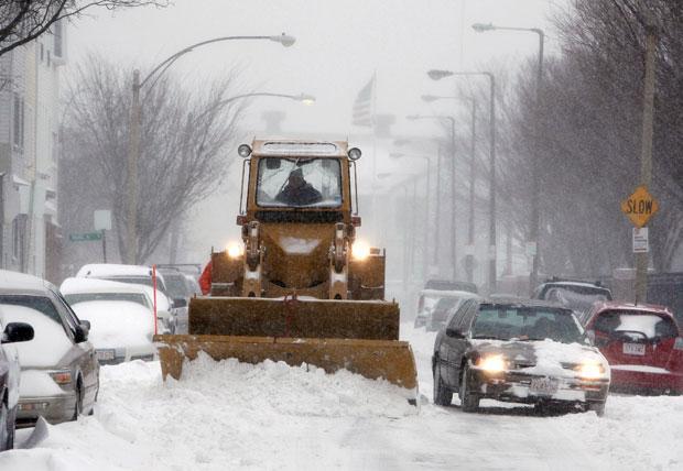A snow plow clears a street in Boston on Sunday. (Michael Dwyer/AP)