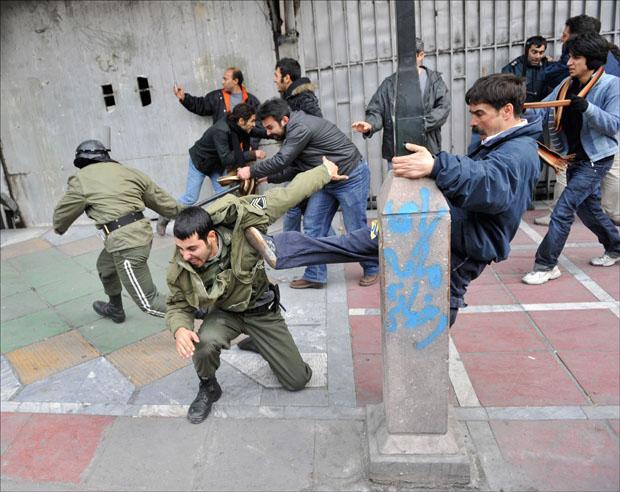 Iranian protesters beat police officers during anti-government protest in Tehran on Sunday. (AP Photo)