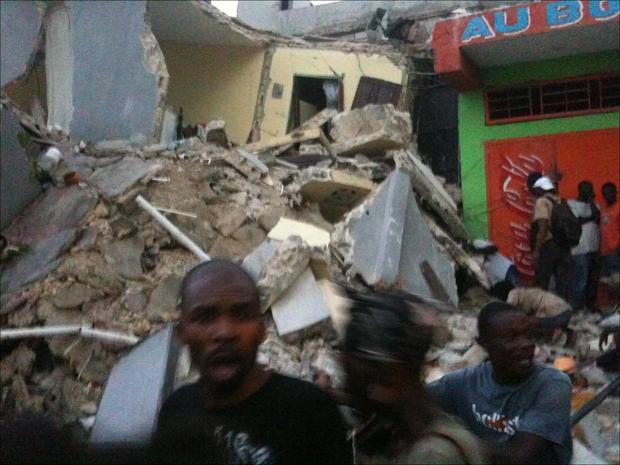 People run past rubble of a damaged building in Port-au-Prince, Haiti, after the largest earthquake ever recorded in the area shook the capitol on Tuesday (Carel Pedre/AP)