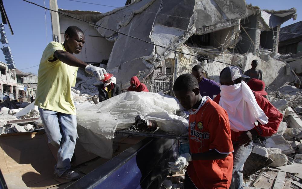 A dead body is brought out from a collapsed building in Port-au-Prince, Haiti. (AP) 
