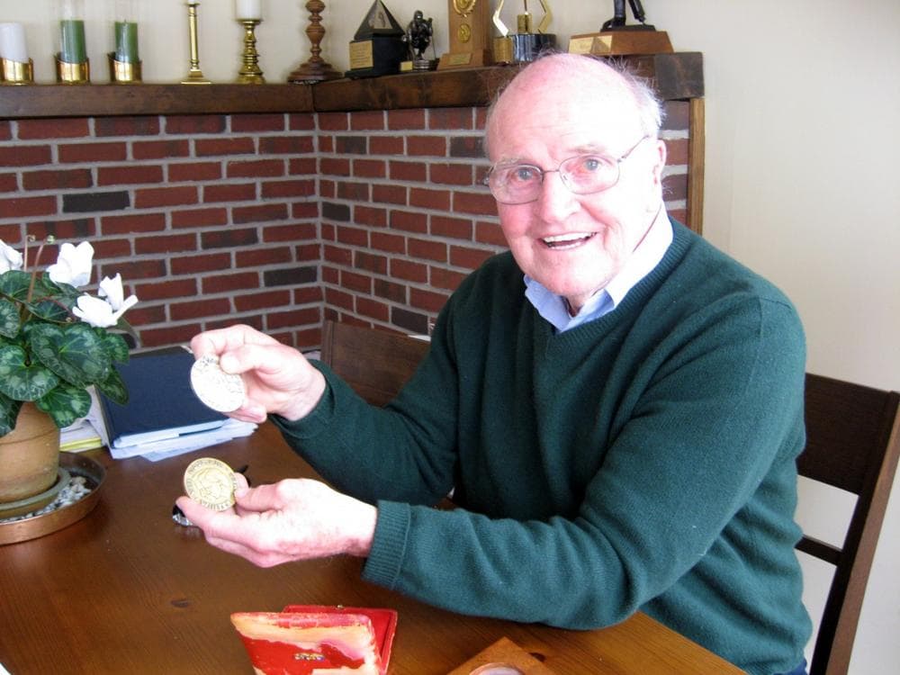 Bill Cleary, at home in Newton, displays the silver medal he won at the 1956 Olympics and his &quot;miracle&quot; gold medal from the 1960 Olympics. (Karen Pelland/WBUR