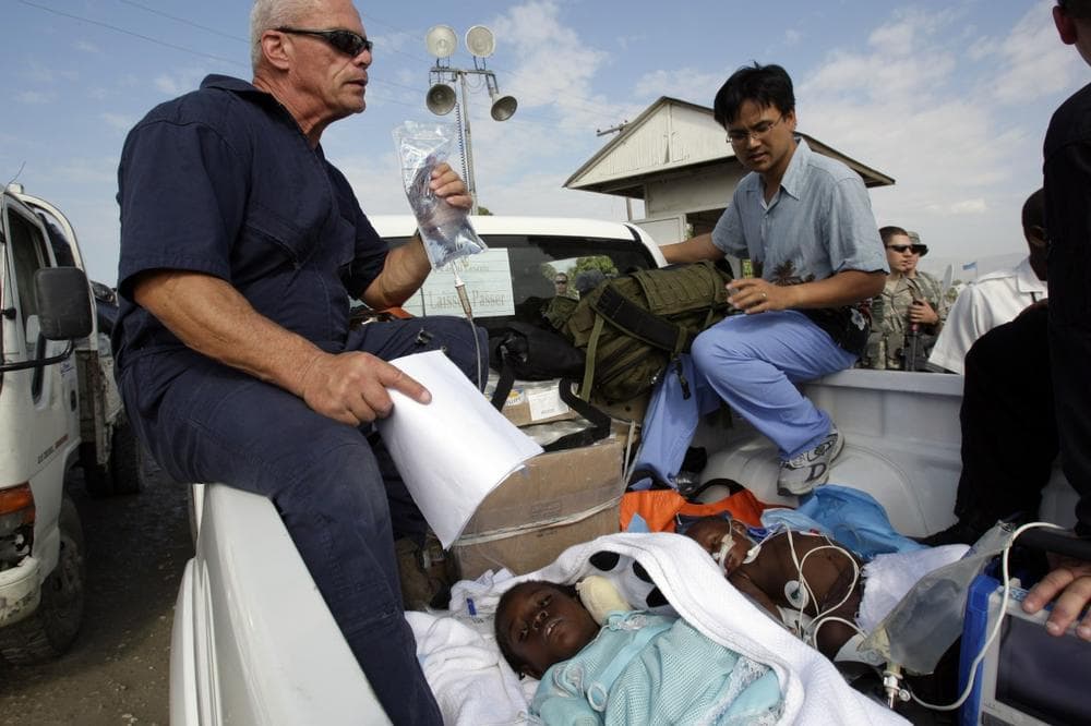 Dr. Phuoc Le of Boston (top right) and a pilot transfer two Haitian earthquake victims to a private jet so they can be flown to the U.S. for treatment arranged by Boston-based Partners In Health. (AP)