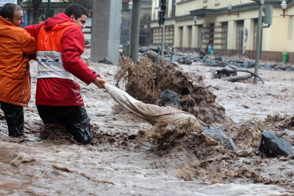 A man is helped while trying to cross a flooded street in Funchal, the Madeira Island's capital, on Saturday. Heavy rain caused flash floods all around the Portuguese island. (Octavio Passos/AP)
