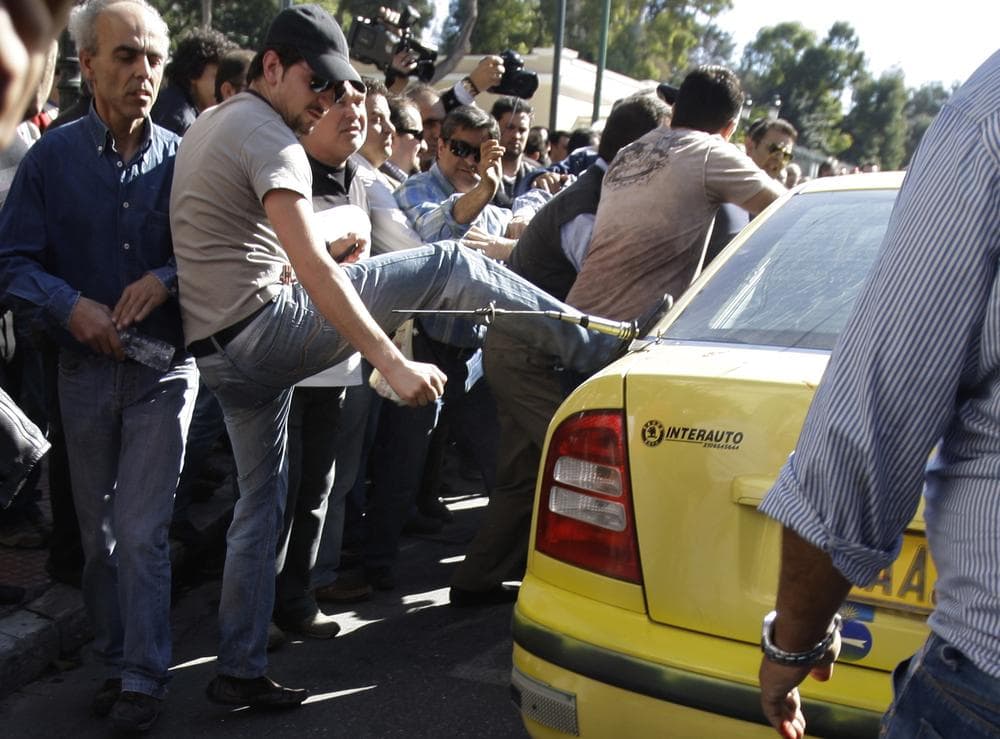 Taxi drivers in Athens batter the cab of a colleague who broke a 2-day nationwide union strike that began today (AP)