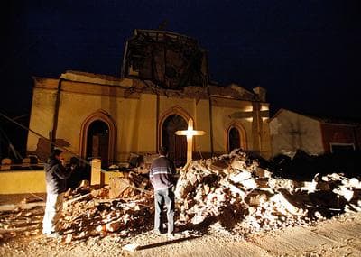 People stand next to the destroyed cathedral of Chanco, some 180 miles southwest of Santiago on Sunday. (AP)