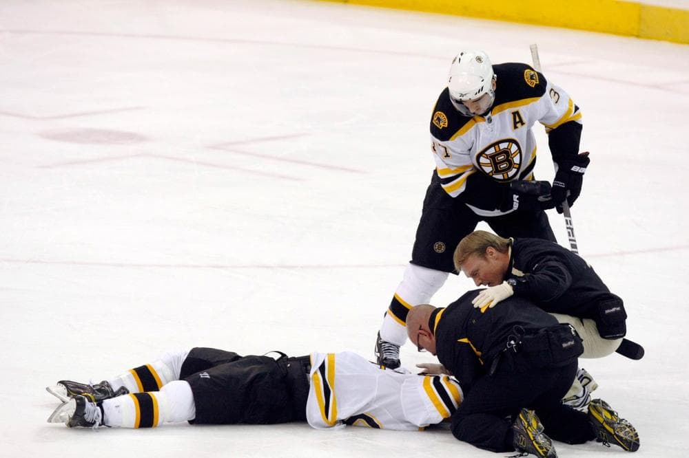 Boston Bruins' Patrice Bergeron, top, watches as trainers look over teammate Marc Savard after he was hit in the third period of an NHL hockey game against the Pittsburgh Penguins in Pittsburgh, Sunday, March 7, 2010. The Penguins won 2-1. (AP)
