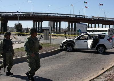 Soldiers stand at a crime scene where the crashed car of a U.S. Consulate employee sits in Ciudad Juarez, Mexico on Sunday. The employee and her husband were shot to death Saturday in the car, with their baby unharmed in the backseat, near the Santa Fe International Bridge linking Ciudad Juarez with El Paso, Texas. (AP)