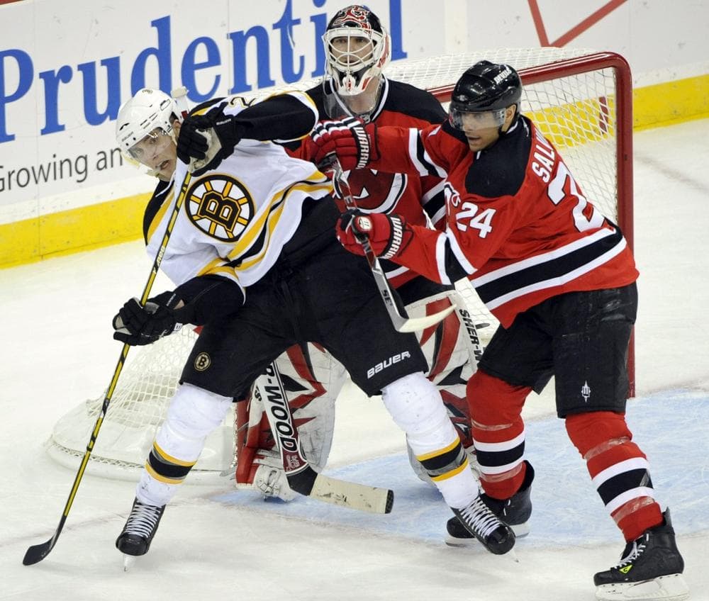 New Jersey Devils' Bryce Salvador, right, checks Boston Bruins' Blake Wheeler, left, in front of Devils goaltender Martin Brodeur during the third period of an NHL hockey game Monday, March 15, 2010, in Newark, N.J. The Devils beat the Bruins 3-2. (AP Photo)