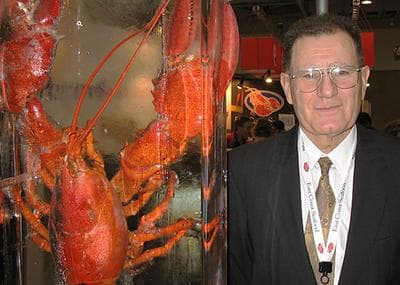 Spiros Tourkakis, of East Coast Seafood, stands next to a 20-pound lobster at the International Boston Seafood Show Tuesday. (Monica Brady-Myerov/WBUR)