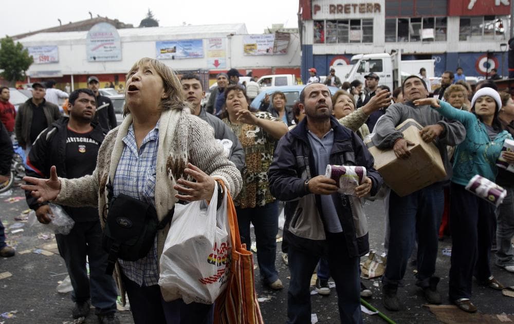 People wait to catch goods thrown from a supermarket window during sporadic looting in Concepcion, Chile following Saturday&#039;s earthquake (AP)