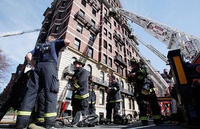 Firefighters regroup at the site of a nine-alarm fire on Beacon Street in Boston on Wednesday. Four people were rescued and taken to a hospital after a fire at the 10-story condominium building, fire officials said. (AP)